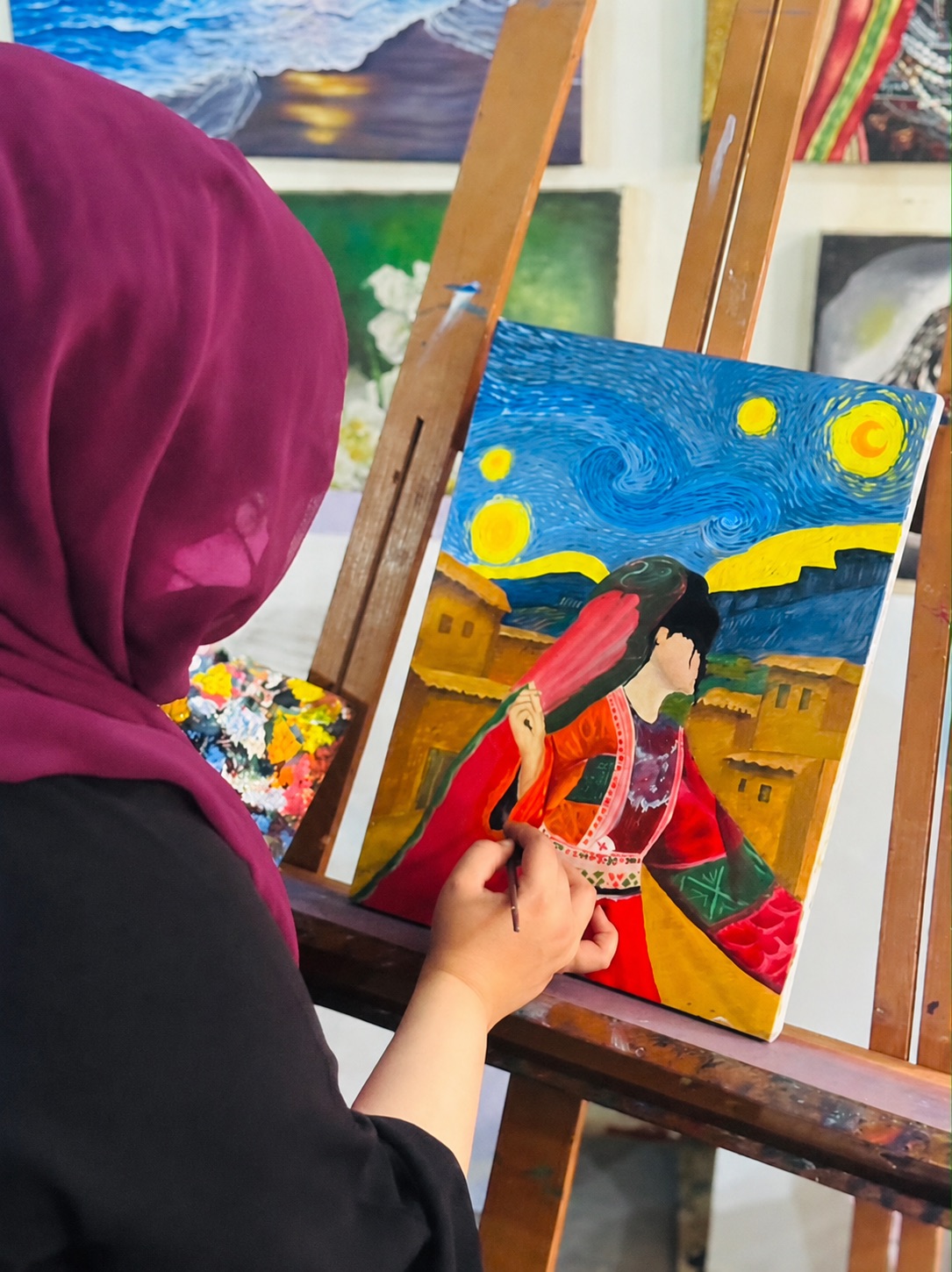 Zuhra painting a colorful portrait at her easel